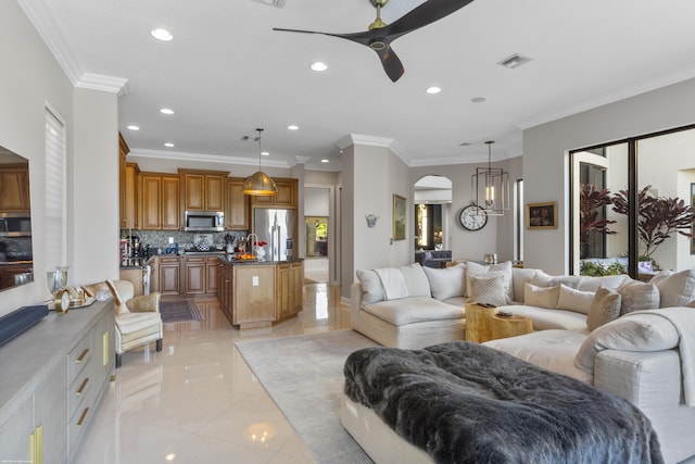 living room featuring ceiling fan with notable chandelier, ornamental molding, and a healthy amount of sunlight