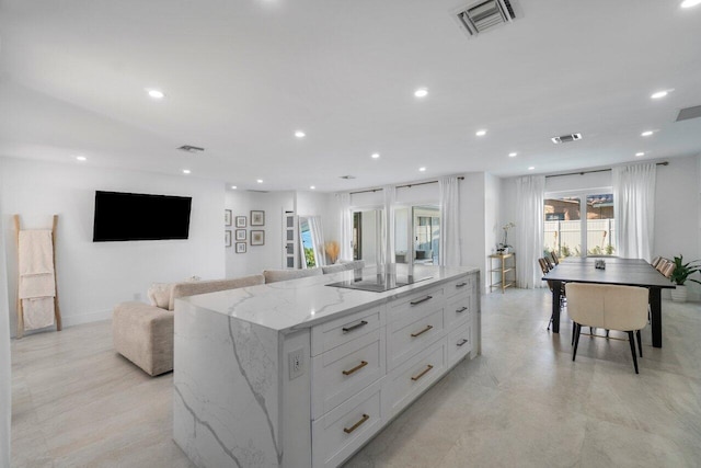 kitchen featuring light stone counters, white cabinets, black electric cooktop, and a kitchen island