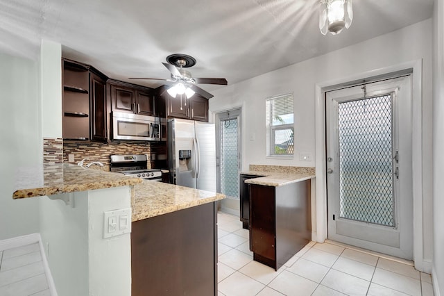 kitchen featuring ceiling fan, backsplash, kitchen peninsula, light stone countertops, and stainless steel appliances