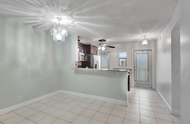 kitchen featuring ceiling fan with notable chandelier, pendant lighting, stainless steel appliances, kitchen peninsula, and light tile patterned floors