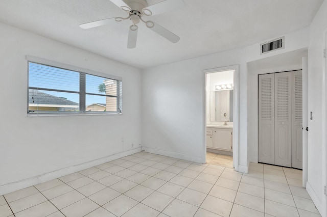 unfurnished bedroom featuring ceiling fan, light tile patterned floors, a closet, and connected bathroom