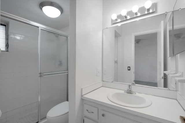 bathroom featuring toilet, vanity, and a shower with door