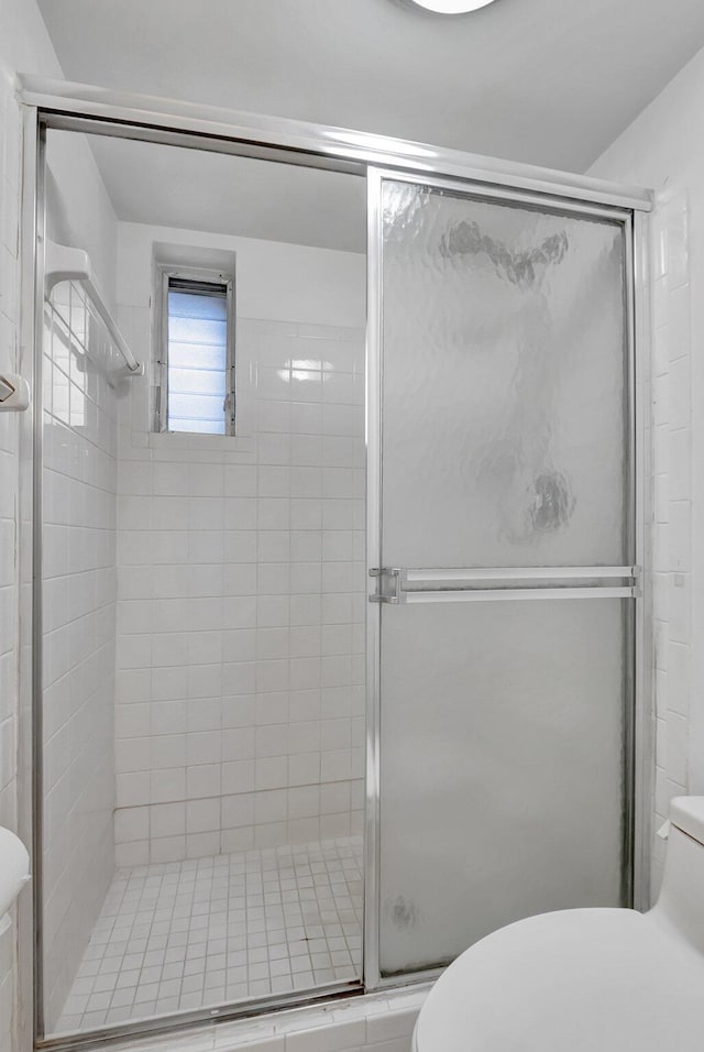 bathroom featuring a shower with shower door and toilet