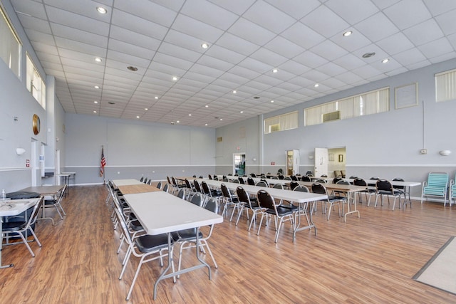 dining room featuring wood-type flooring, a paneled ceiling, and a towering ceiling