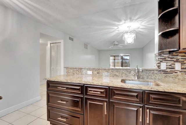 kitchen featuring ceiling fan, tasteful backsplash, light stone countertops, dark brown cabinetry, and sink