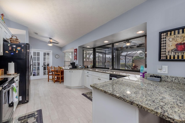 kitchen with white cabinetry, stainless steel appliances, vaulted ceiling, and french doors