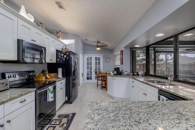 kitchen featuring vaulted ceiling, sink, white cabinets, light stone counters, and stainless steel appliances