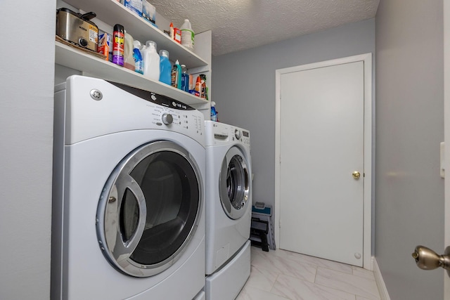 clothes washing area with washing machine and dryer and a textured ceiling