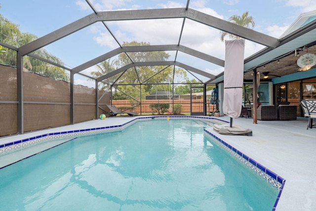 view of swimming pool with glass enclosure, a patio area, and ceiling fan