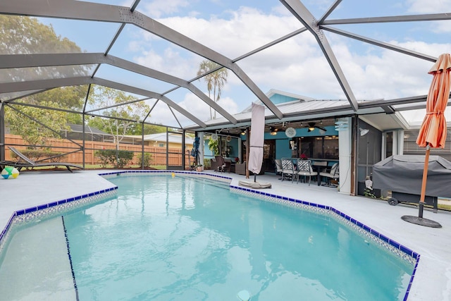 view of pool with glass enclosure, area for grilling, ceiling fan, and a patio