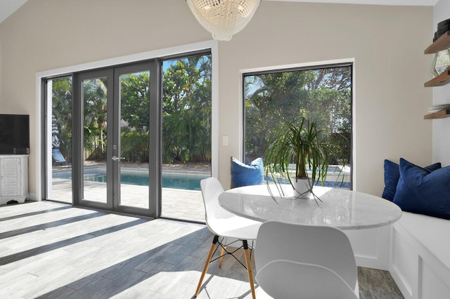 dining area with french doors, vaulted ceiling, and a notable chandelier