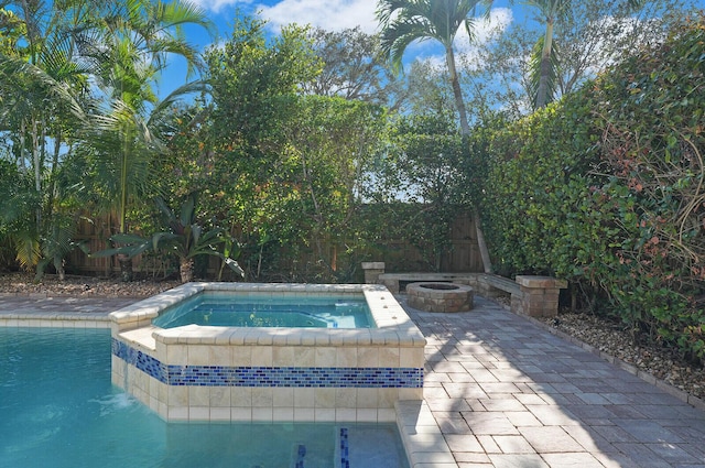 view of swimming pool featuring an in ground hot tub, a fire pit, and a patio