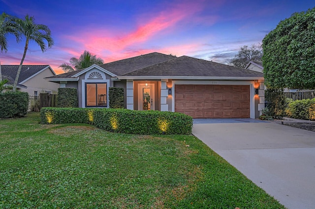 ranch-style house featuring a garage and a yard