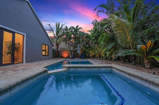 pool at dusk featuring an in ground hot tub