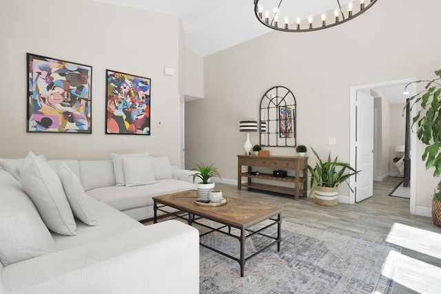 living room with high vaulted ceiling, light hardwood / wood-style flooring, and a notable chandelier