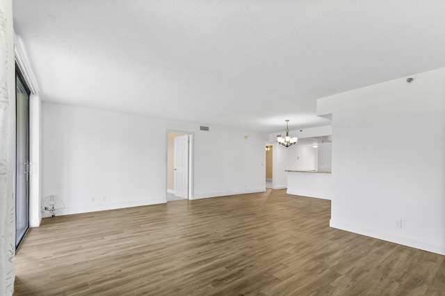 unfurnished living room featuring an inviting chandelier and hardwood / wood-style flooring