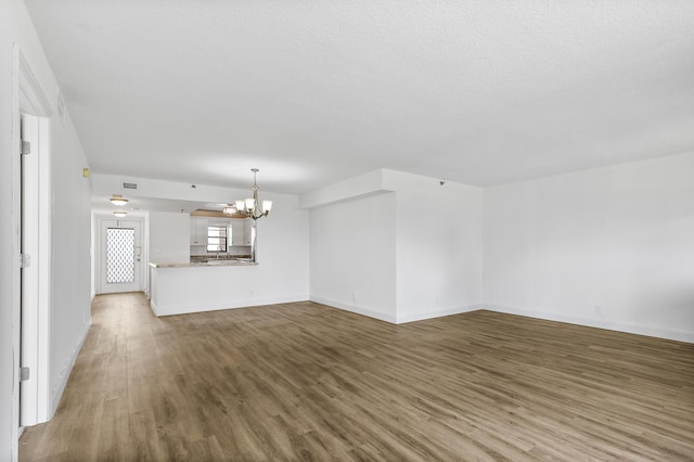 unfurnished living room with a chandelier and hardwood / wood-style floors