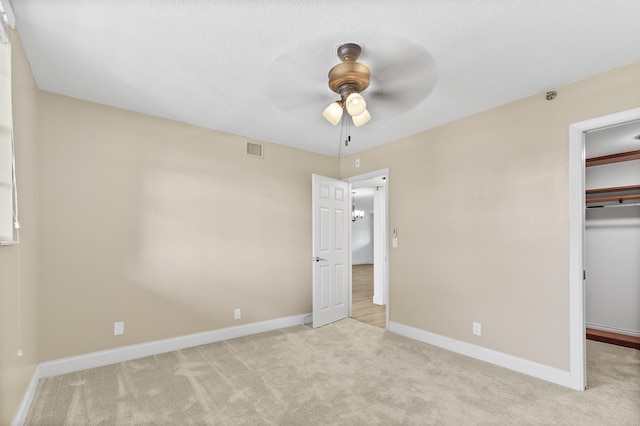 unfurnished bedroom with a spacious closet, ceiling fan, a closet, and light colored carpet