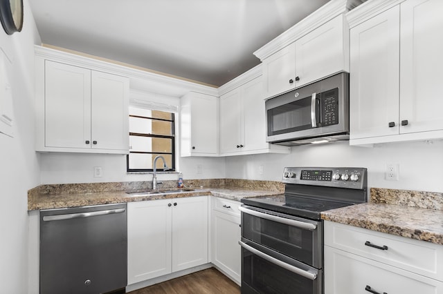 kitchen with white cabinets, appliances with stainless steel finishes, dark wood-type flooring, sink, and stone countertops