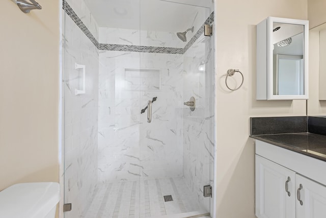 bathroom featuring vanity, toilet, and a shower with door