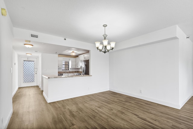 kitchen with stainless steel fridge with ice dispenser, white cabinetry, kitchen peninsula, dark hardwood / wood-style floors, and a chandelier