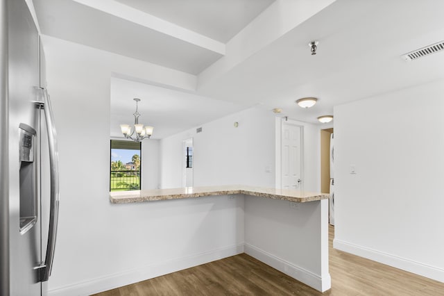 kitchen featuring pendant lighting, stainless steel fridge with ice dispenser, kitchen peninsula, a chandelier, and light wood-type flooring