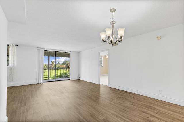 unfurnished room featuring hardwood / wood-style flooring, expansive windows, and a notable chandelier