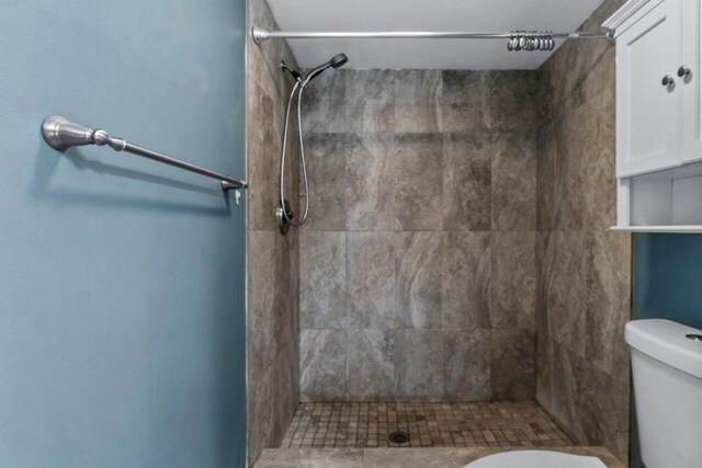 bathroom featuring toilet and a tile shower