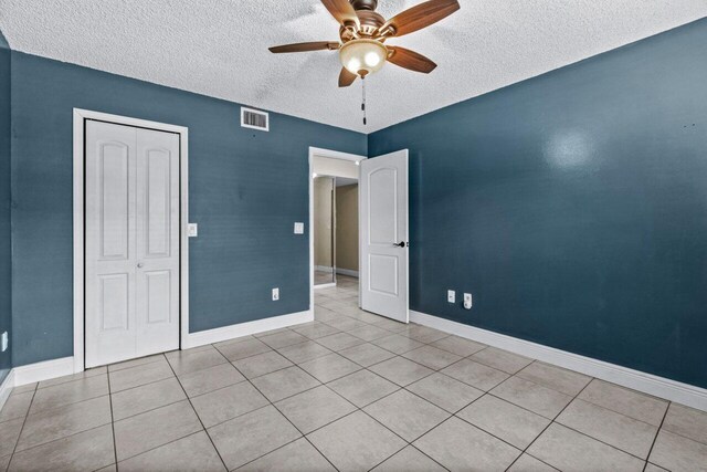 unfurnished room with a textured ceiling, ceiling fan, and light tile patterned floors