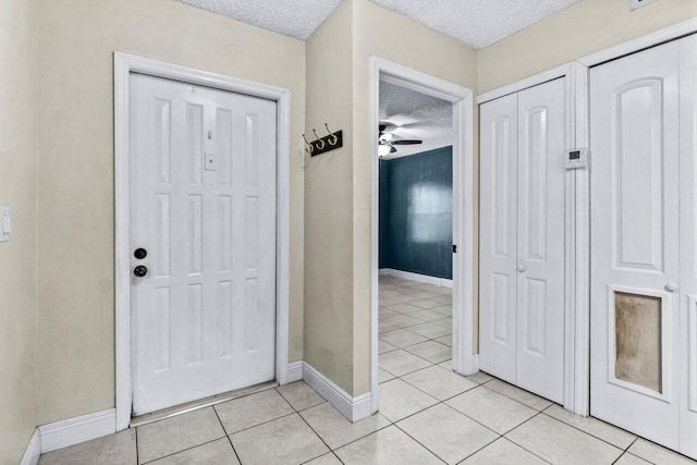 foyer featuring ceiling fan, light tile patterned floors, and a textured ceiling