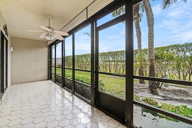 unfurnished sunroom featuring ceiling fan and a healthy amount of sunlight