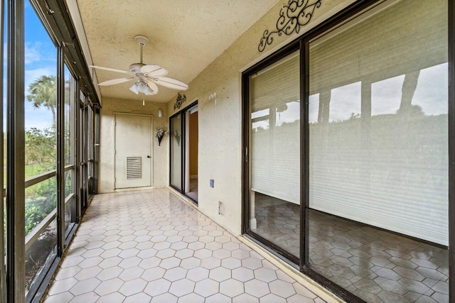 unfurnished sunroom featuring ceiling fan and plenty of natural light