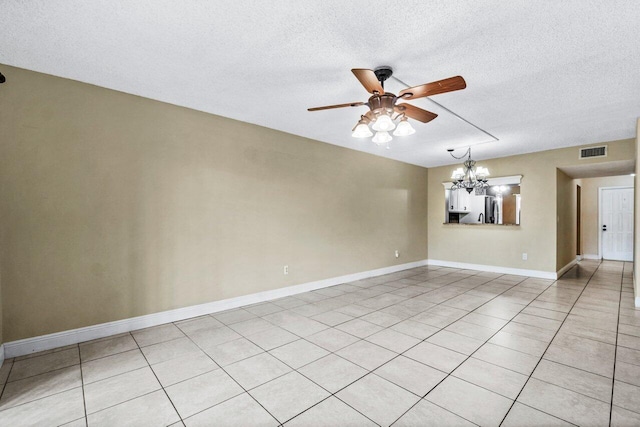 tiled spare room featuring ceiling fan with notable chandelier and a textured ceiling