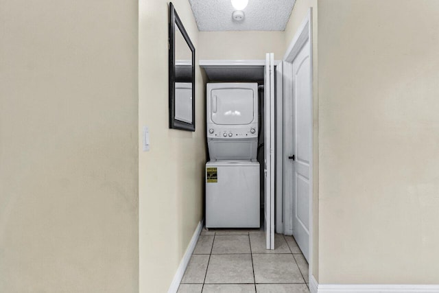 washroom with stacked washing maching and dryer, light tile patterned floors, and a textured ceiling