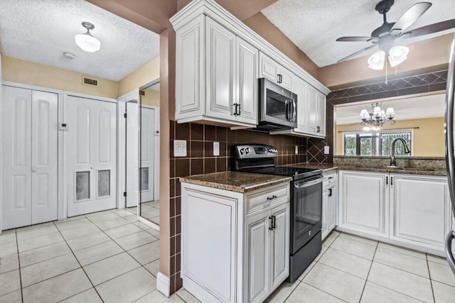 kitchen with ceiling fan with notable chandelier, white cabinetry, light tile patterned floors, and range with electric cooktop