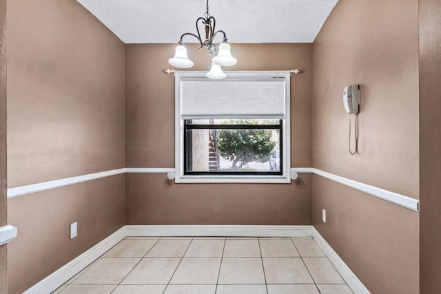 unfurnished dining area featuring light tile patterned floors, an inviting chandelier, and a textured ceiling