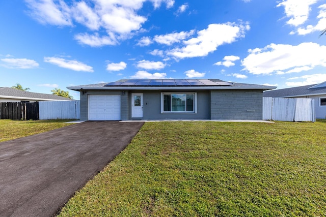 single story home with a front lawn, solar panels, and a garage