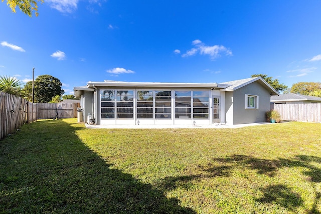 rear view of house with a sunroom and a lawn