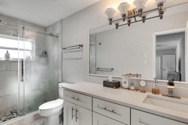 bathroom featuring a shower with shower door, toilet, and vanity