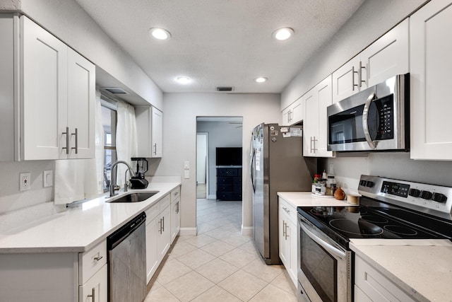 kitchen with light tile patterned floors, stainless steel appliances, white cabinets, and sink