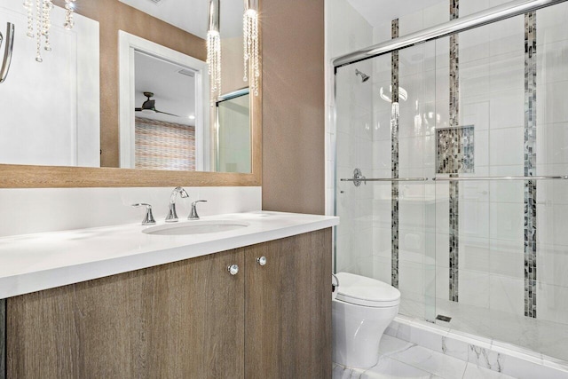 bathroom with a shower with door, vanity, ceiling fan, and toilet