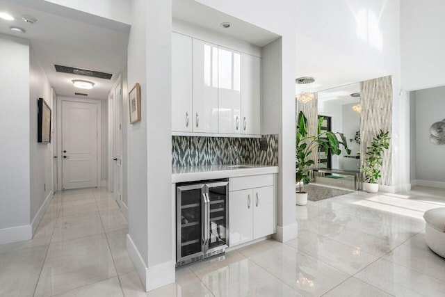 bar featuring white cabinetry, wine cooler, and backsplash