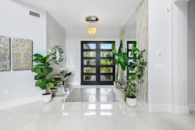 tiled foyer with an inviting chandelier and french doors