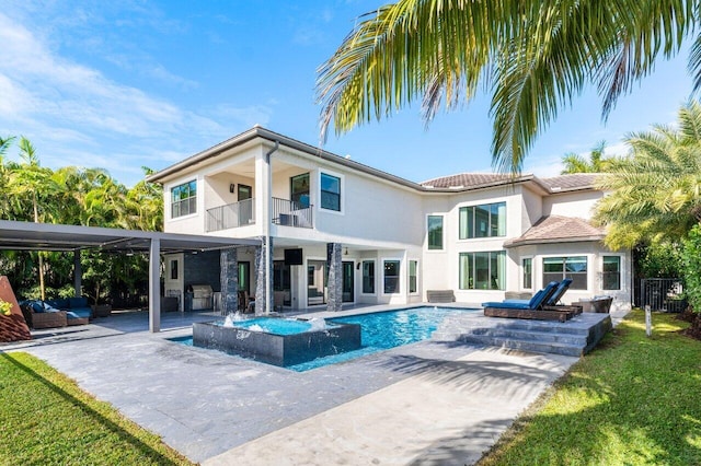 rear view of property featuring a patio, a balcony, and a pool with hot tub