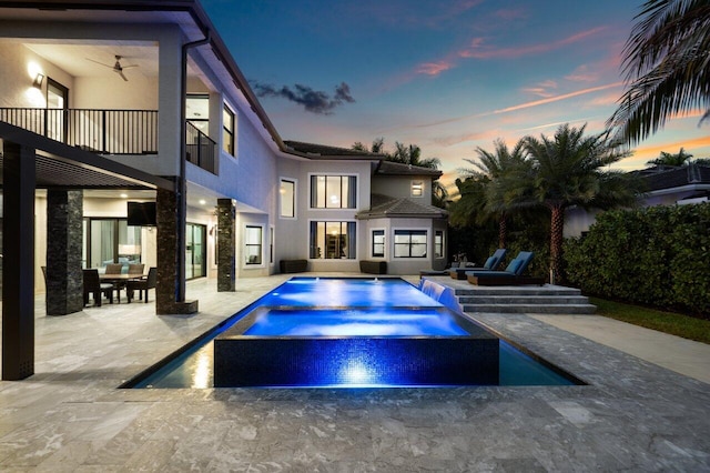 pool at dusk with an in ground hot tub, ceiling fan, and a patio