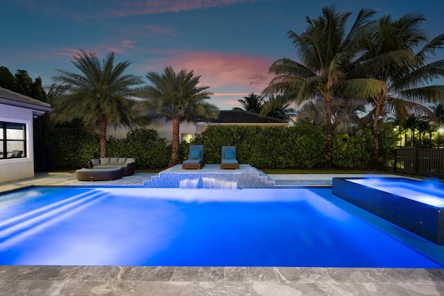 pool at dusk with an in ground hot tub and a patio