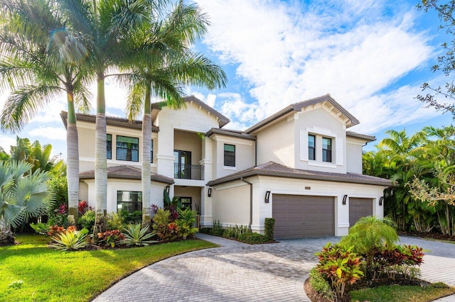 mediterranean / spanish house with a garage, a front yard, and a balcony