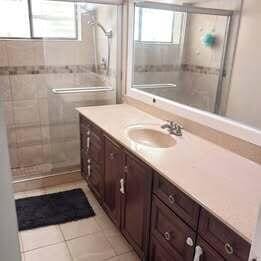 bathroom with tiled shower, tile patterned floors, vanity, and plenty of natural light