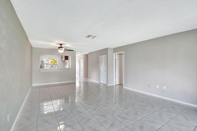 spare room with ceiling fan, a textured ceiling, visible vents, and baseboards