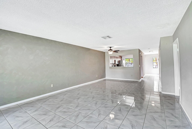 unfurnished living room with a textured ceiling, visible vents, a ceiling fan, and baseboards